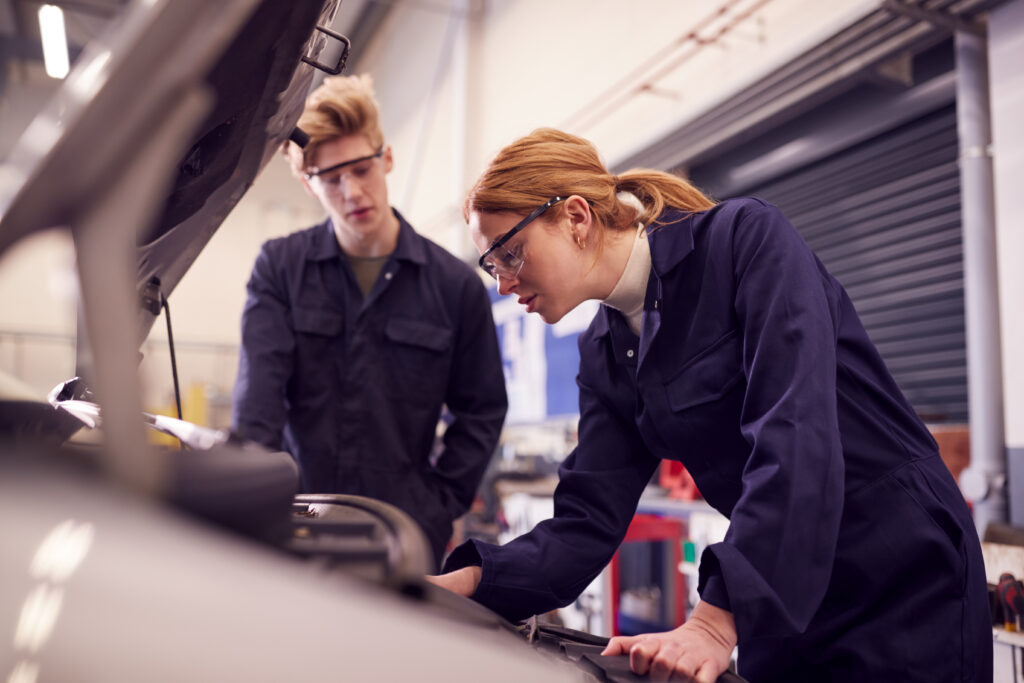 male and female students looking at car engine