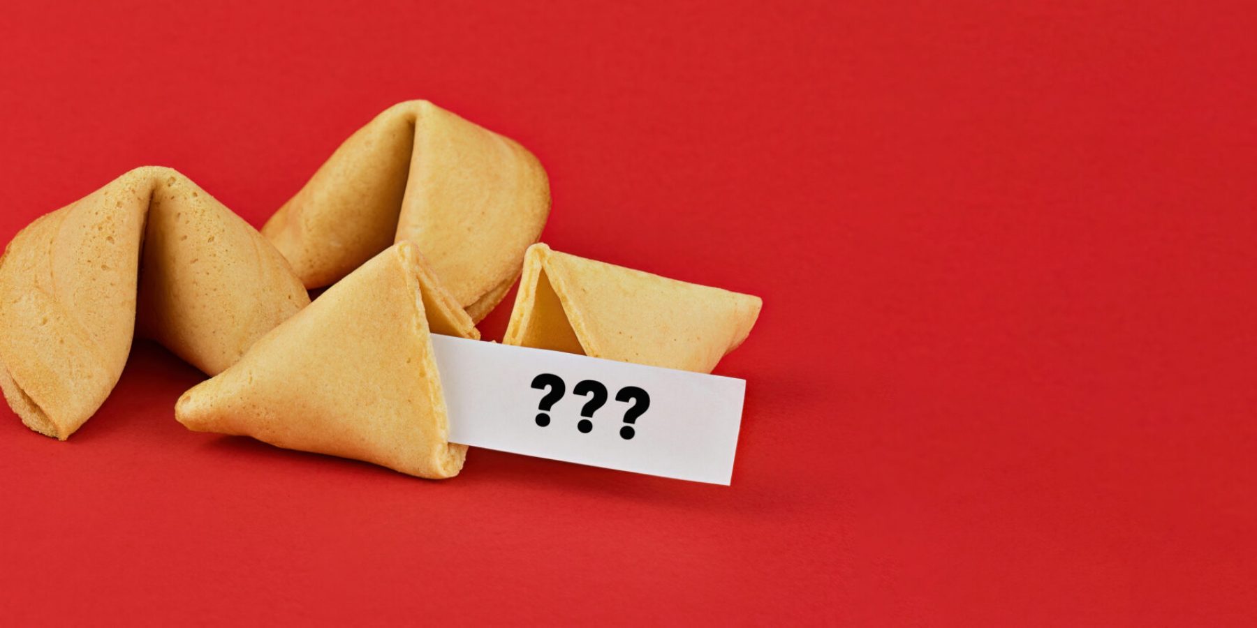 Chinese fortune cookies on red background with question marks note.